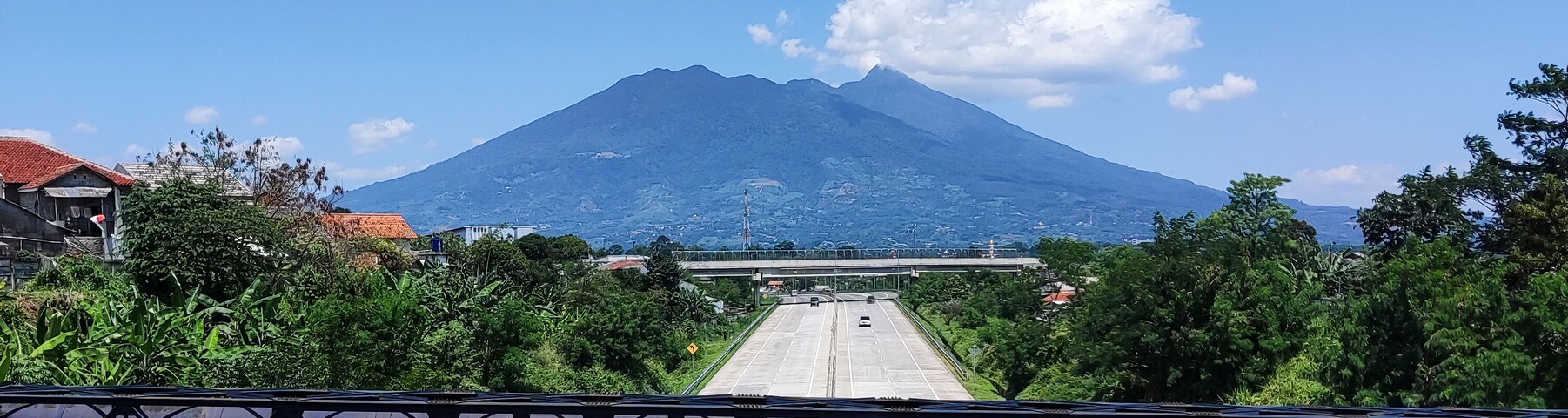 A road leading to a mountain with a clear sky.