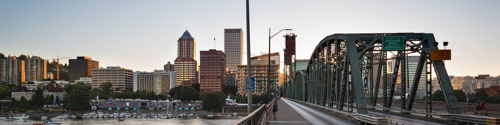 A bridge over a river with a city skyline in the background.