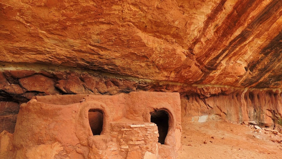 A cave with reddish rock walls and two small openings.