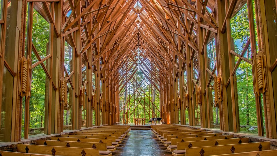 A wooden church interior with a high ceiling and rows of pews.