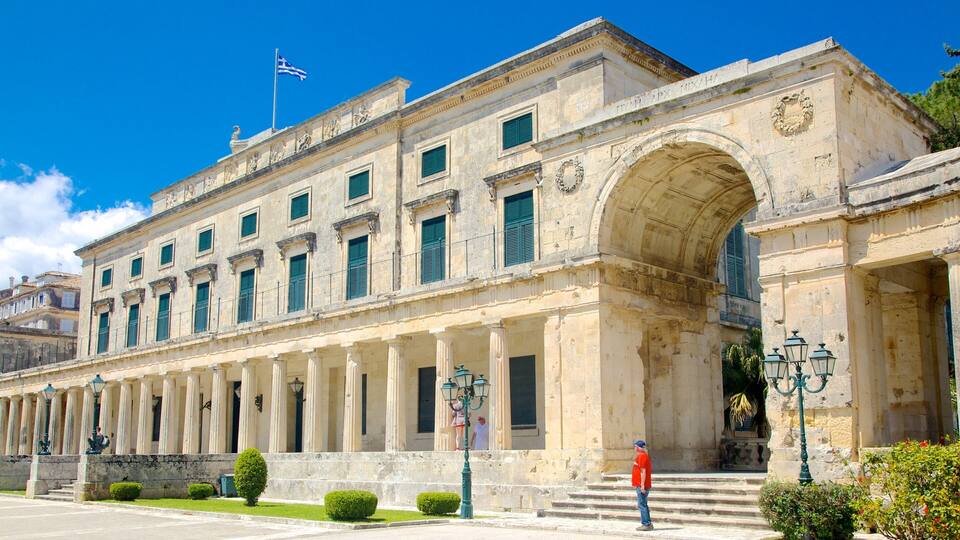 A historic building with classical architecture, featuring columns, a large arched entrance, and a flag on top.