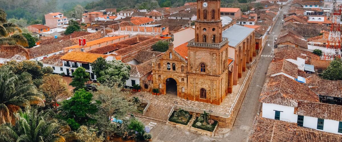 A town with a prominent church featuring a tall bell tower, surrounded by terraced houses with red-tiled roofs.