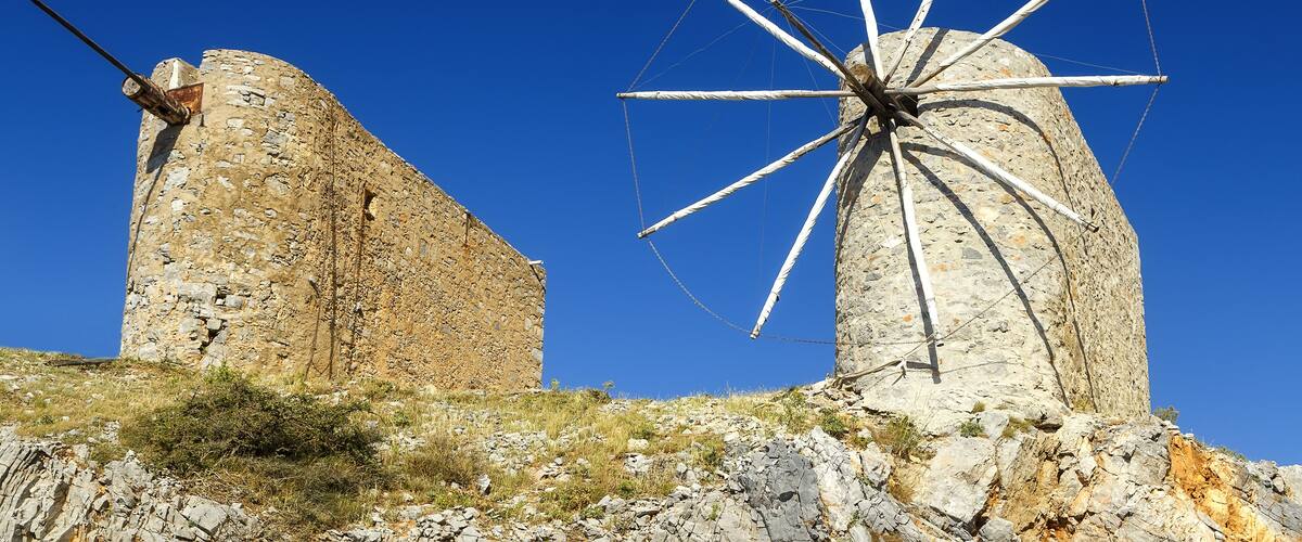 Two windmills on a hill with a clear blue sky.