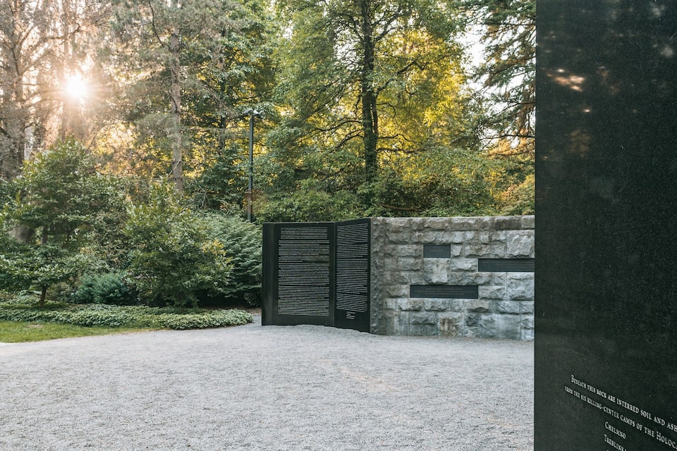 Un memoriale con pietre incise e un vialetto di ghiaia in una zona boschiva.