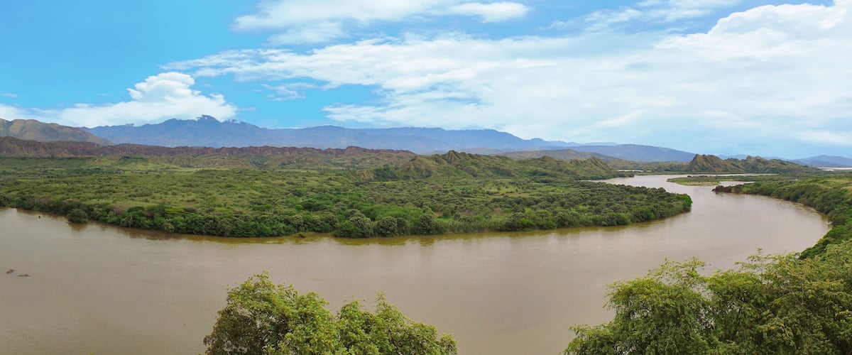 A river winding through a green valley with mountains in the background.