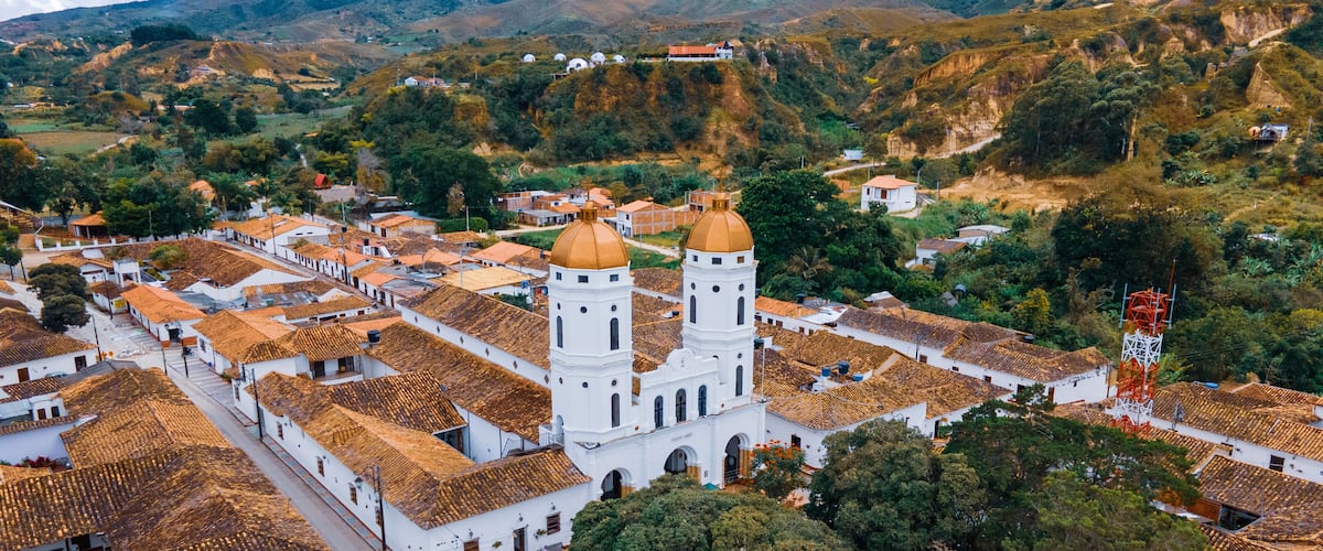 A town with white buildings and a prominent church with two towers.