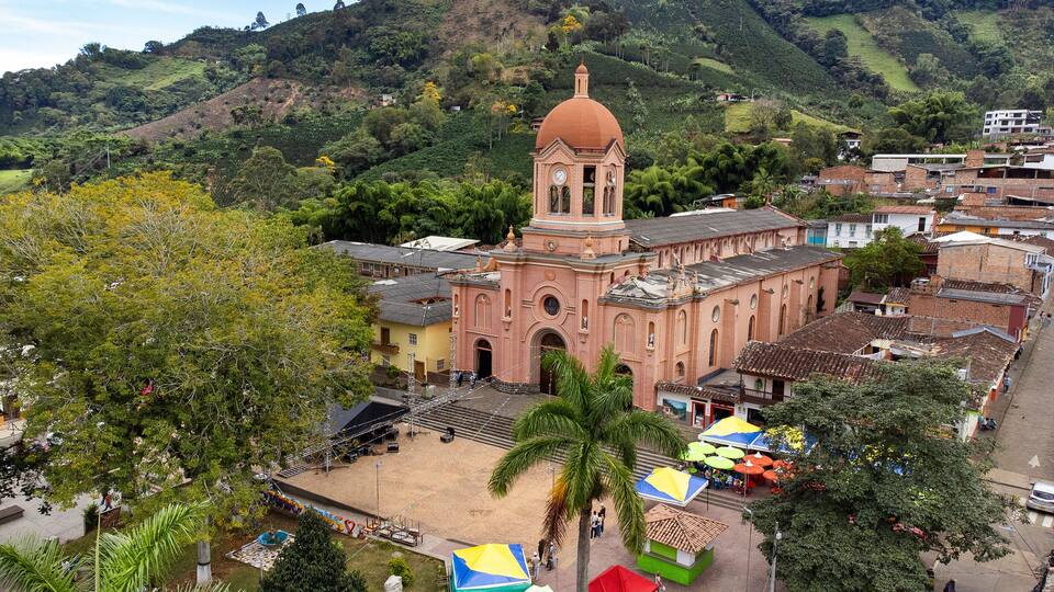 A church with a dome, surrounded by a small town and hills.