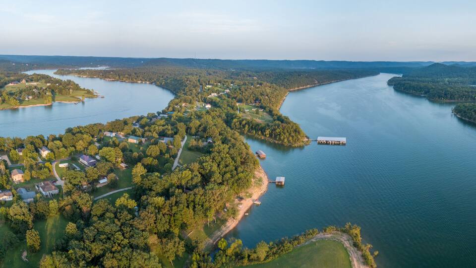 An aerial view of a river winding through a densely forested area with several small islands and a dock.