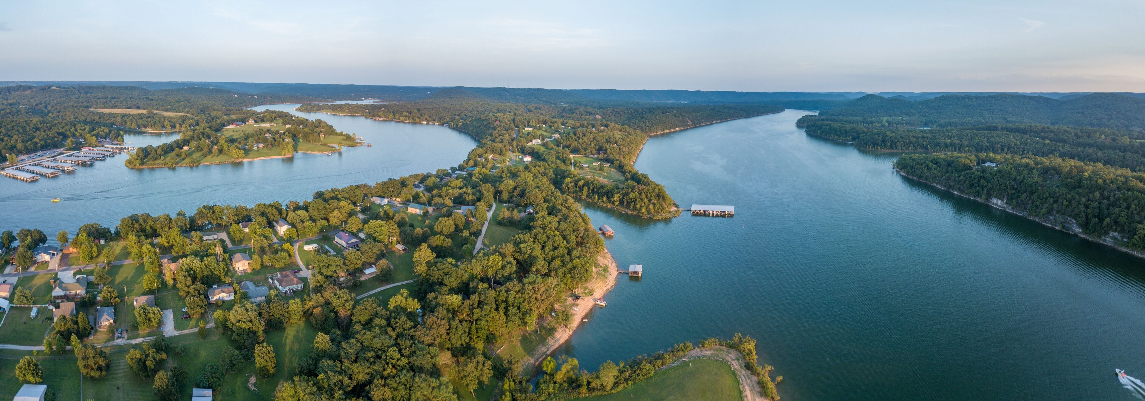An aerial view of a river winding through a densely forested area with several small islands and a dock.