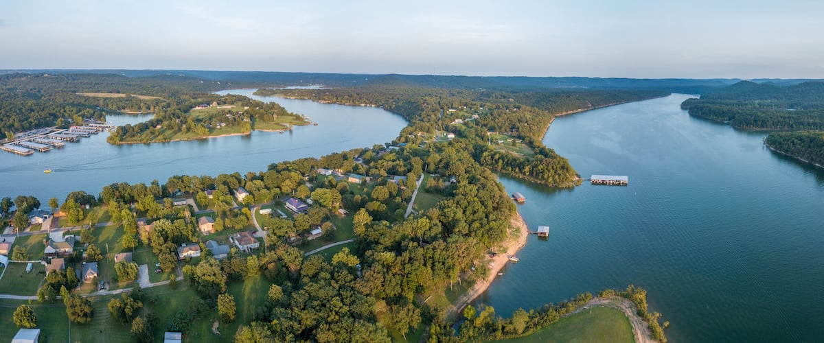 An aerial view of a river winding through a densely forested area with several small islands and a dock.