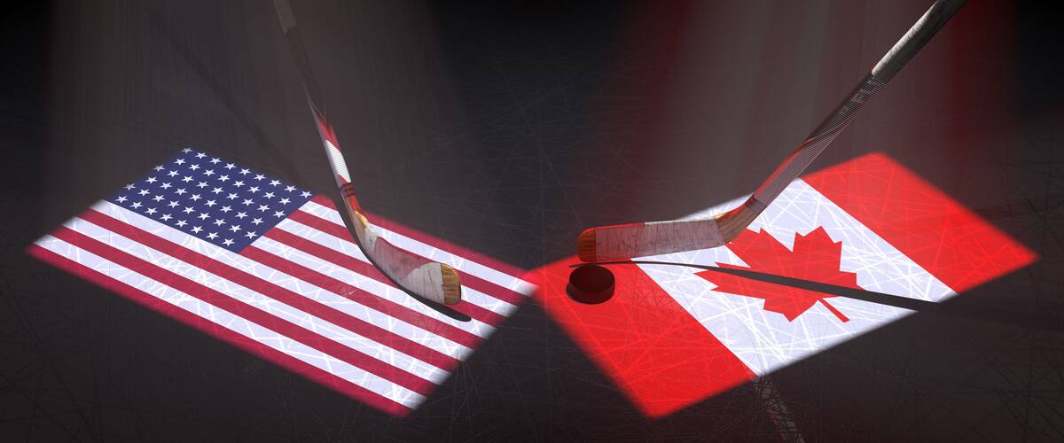 Hockey puck, hockey sticks and the image of the Unites States and Canadian flag on the ice.