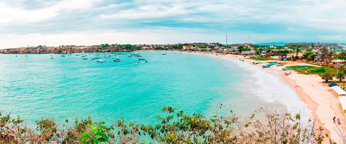 A coastal town with turquoise waters, a sandy beach, and boats.