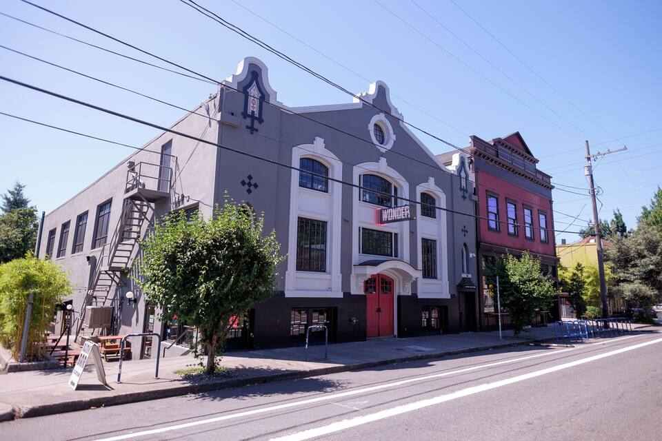 A historic building with a red door and a neon sign that reads "Wonder."