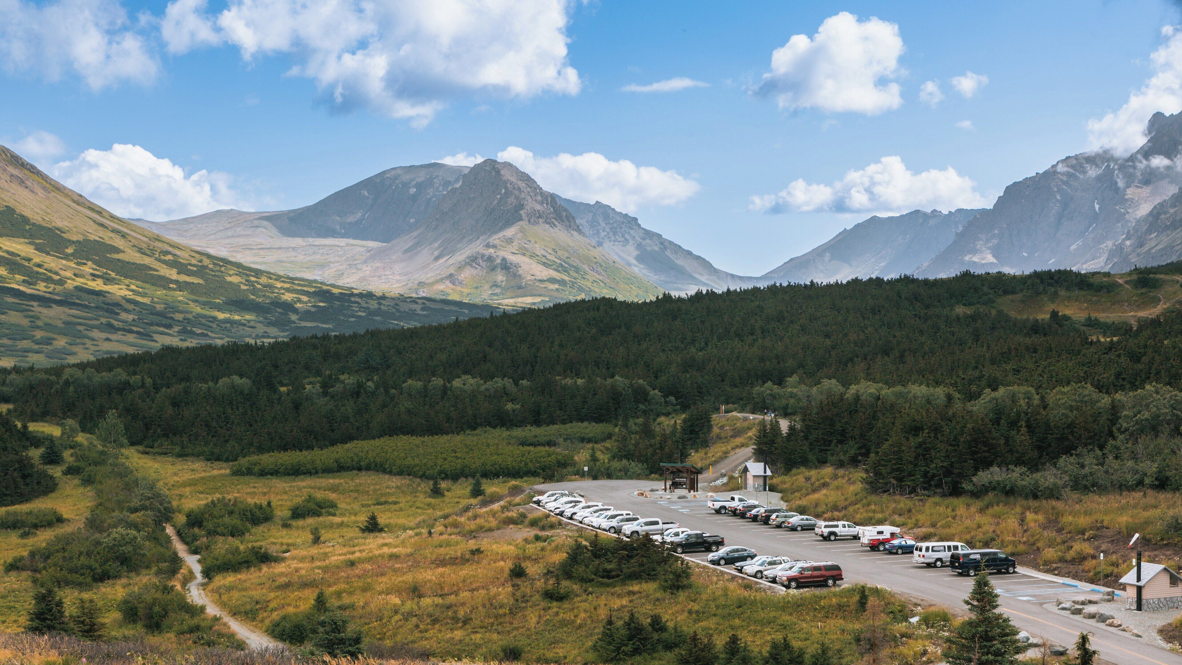 Beautiful view of Flattop Mountain Trail in Anchorage, Alaska on a clear day with parking area filled with visitors ready for outdoor adventures