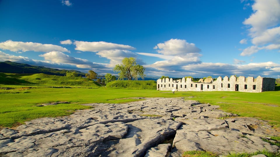 A historic stone building with a grassy field and a rocky foreground.