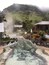 A hot spring area with a pool, surrounded by rocks and plants, and a mountain in the background.