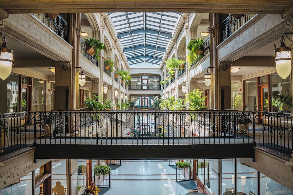 Um grande shopping com vários níveis, um átrio central, varandas com plantas e plantas pendentes.