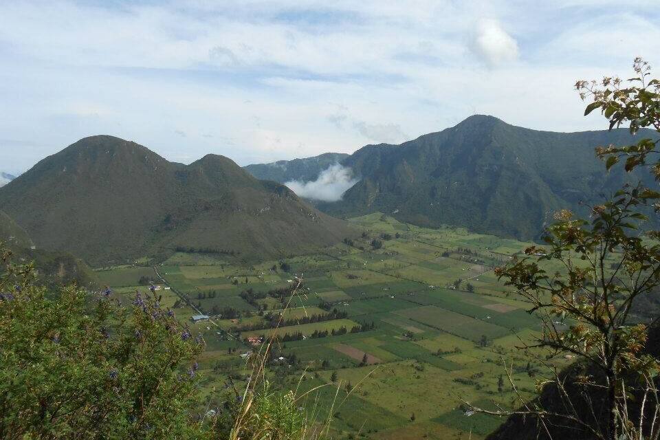 A mountainous landscape with green fields and a small village.