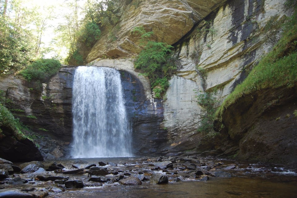 A waterfall cascading down a rocky cliff surrounded by greenery.