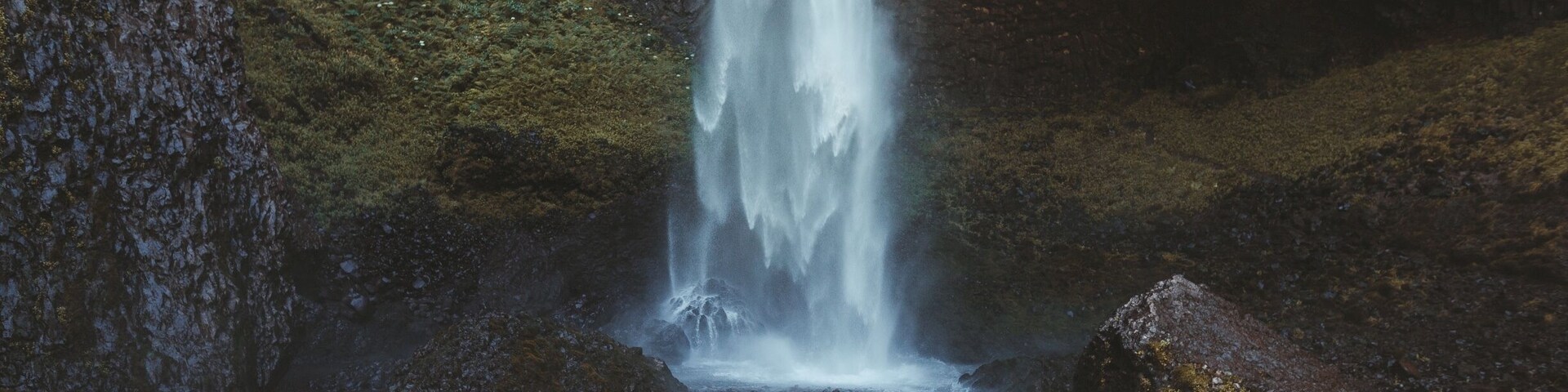 A waterfall cascading down a rocky cliff surrounded by mossy terrain.