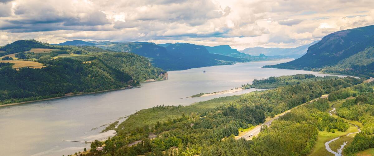 A river winding through a valley with forested hills and a bridge.
