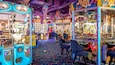 Un salón de juegos lleno de color con diversas máquinas y peluches.