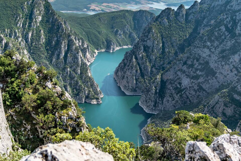 Paisagem montanhosa com um lago azul-turquesa rodeado por penhascos íngremes e vegetação densa.