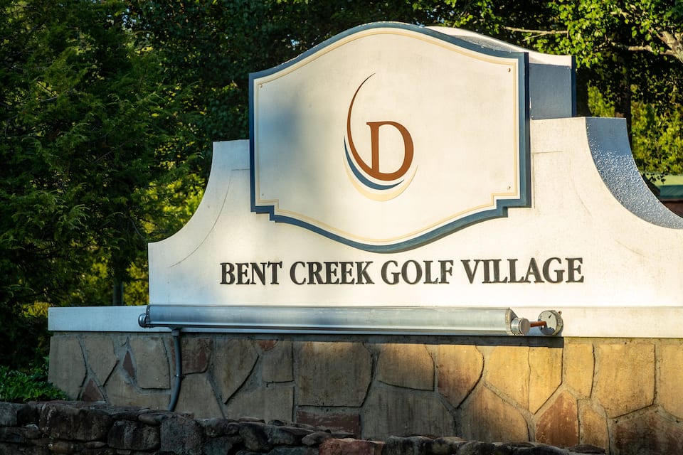 A sign for Bent Creek Golf Village with a stylized 'D' logo.