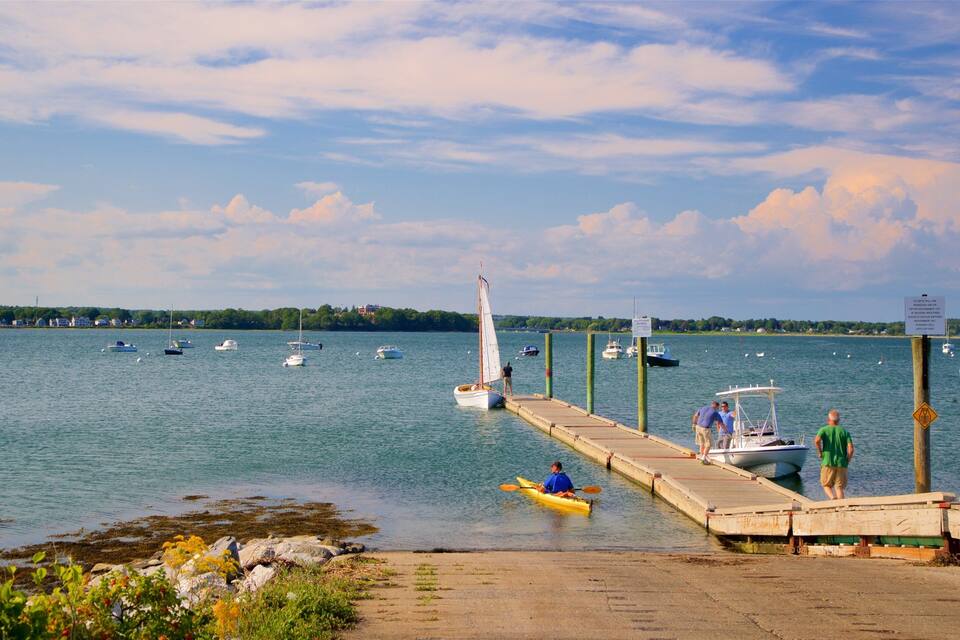 Um lago tranquilo com vários barcos, um cais e um veleiro.