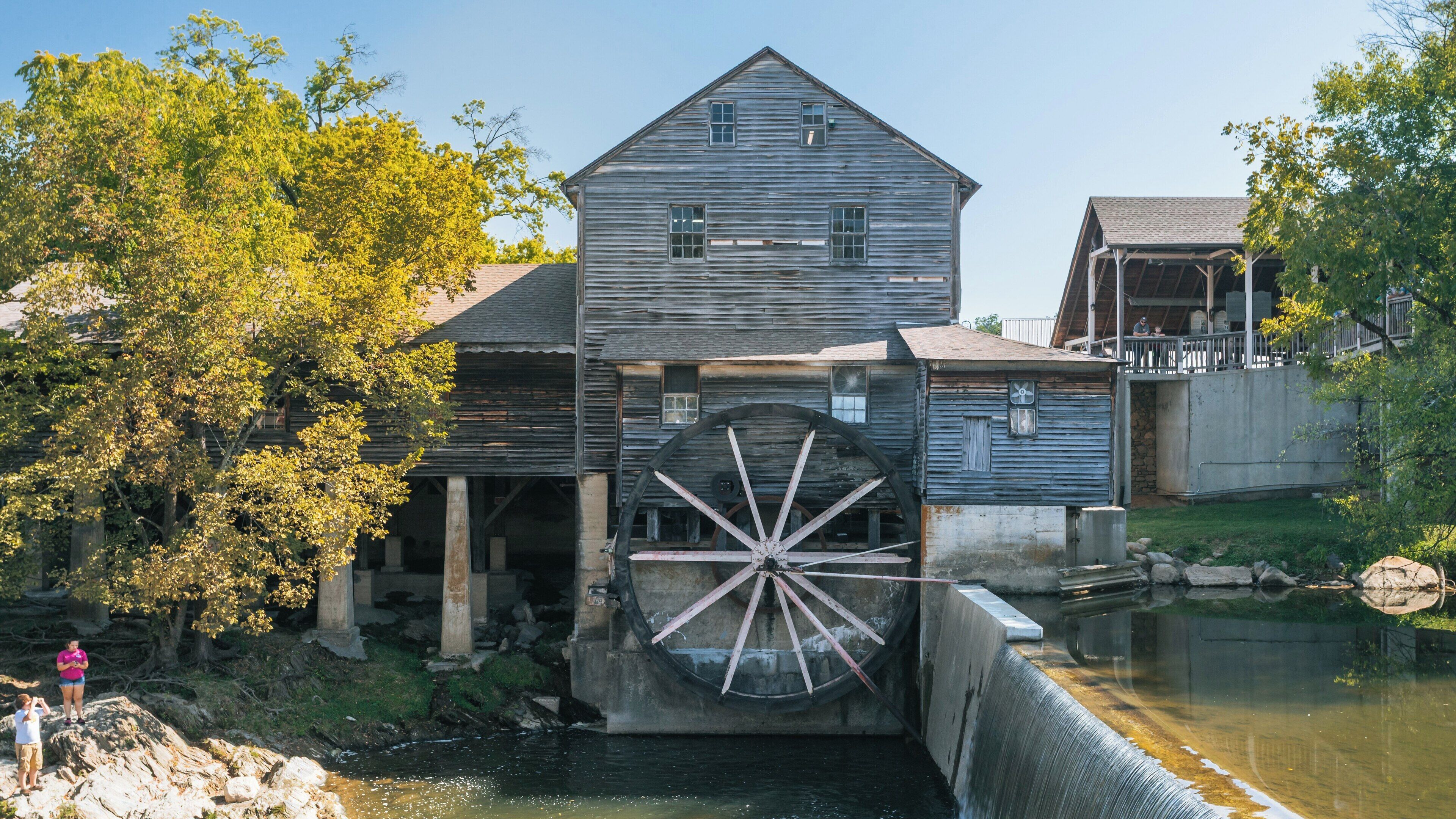Old Mill in Pigeon Forge, Tennessee showcases a historic water wheel beside a serene river with tree-lined banks and visitors enjoying the scenery