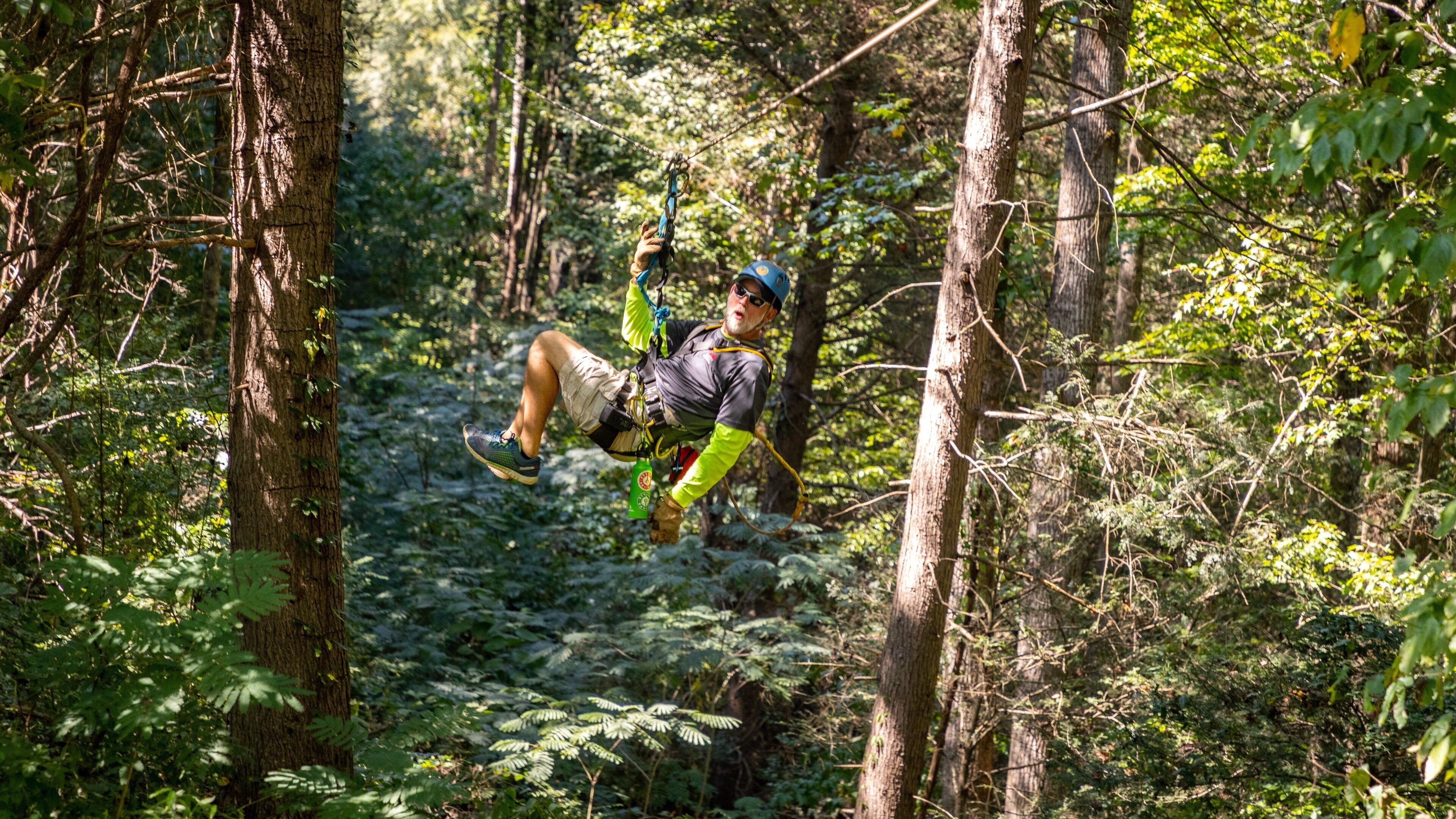 Una persona haciendo tirolesa por un bosque frondoso.