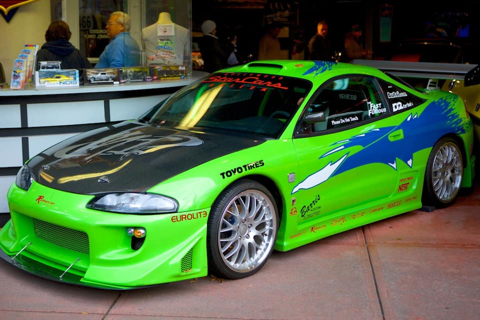 A bright green sports car with sponsor logos and decals, parked indoors.