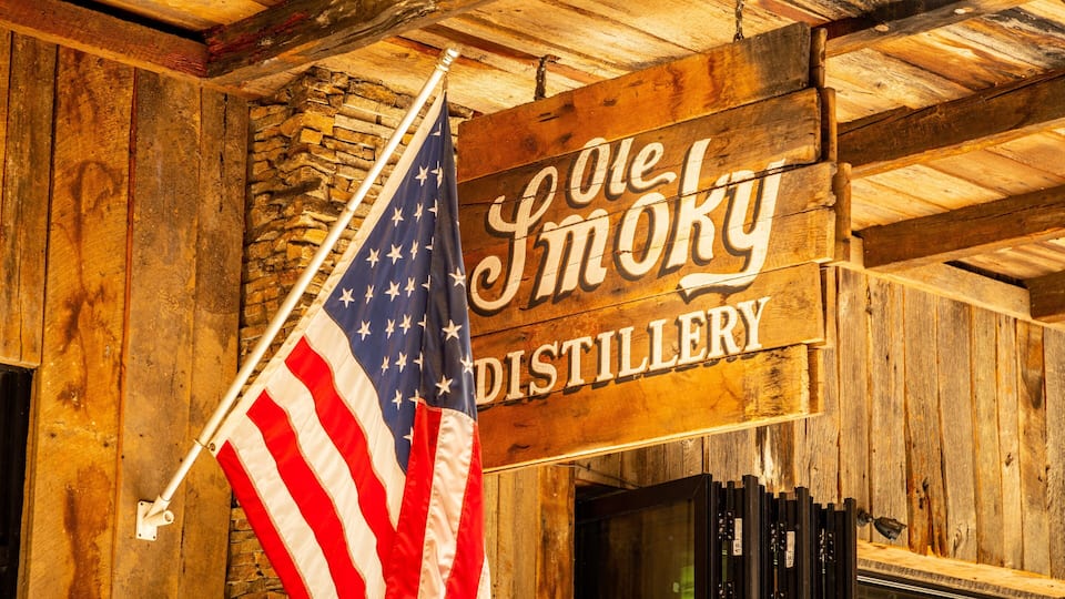 A wooden sign with 'Ole Smoky Distillery' written on it, an American flag, and wooden beams.