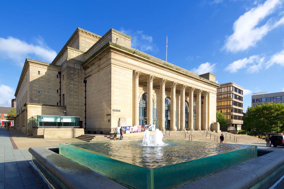 A historic building with large columns and a fountain in front.