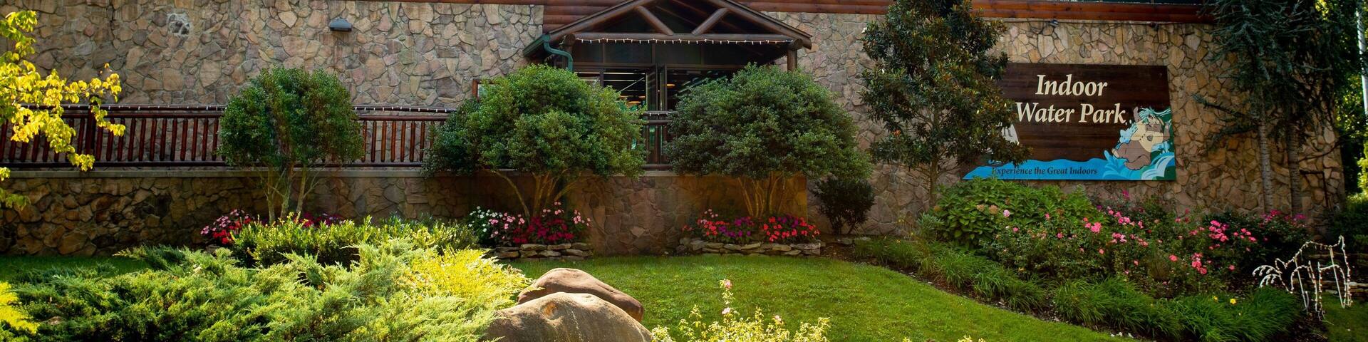 Un edificio grande con fachada de vidrio, rodeado de un jardín ajardinado con diversas plantas y flores.