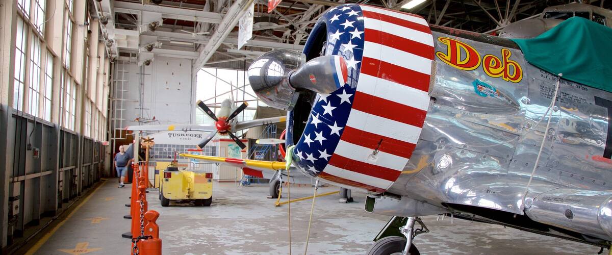 A vintage aircraft with a painted American flag on its side, inside a hangar.