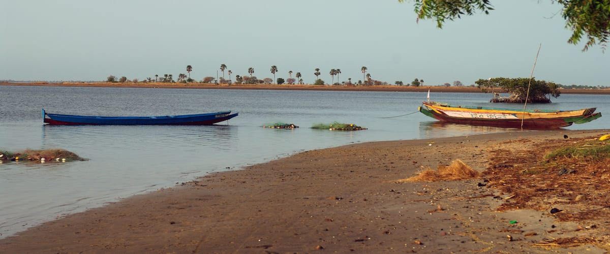 A calm river with boats and a distant shoreline with trees.