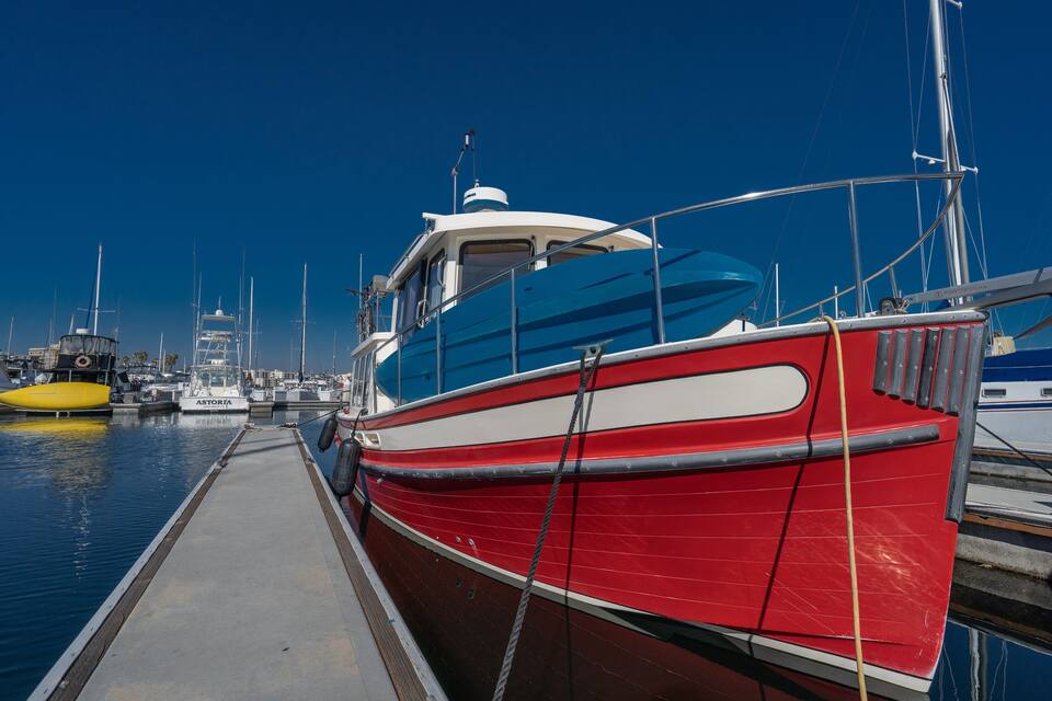 A marina with several boats docked, including a red and white boat prominently in the foreground.
