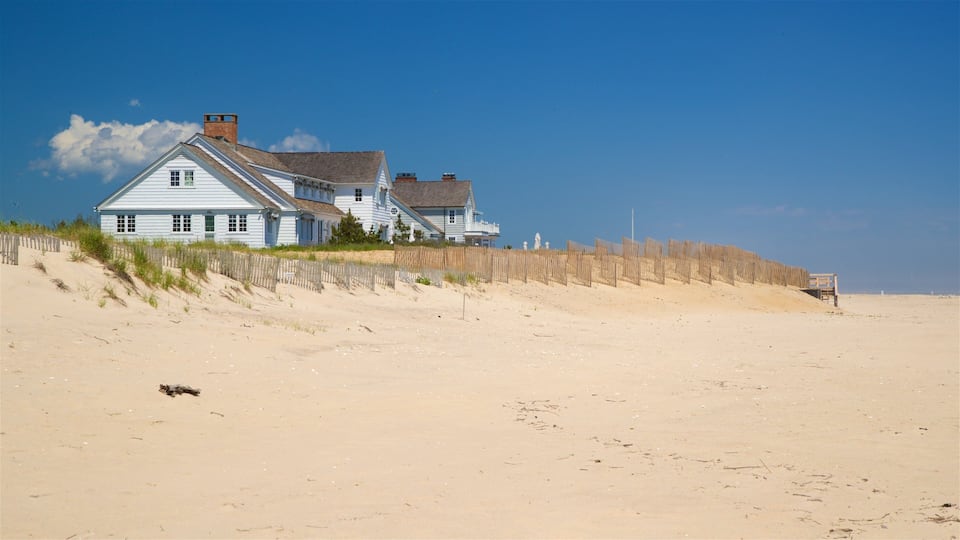 A white house on a sandy beach with a wooden fence.