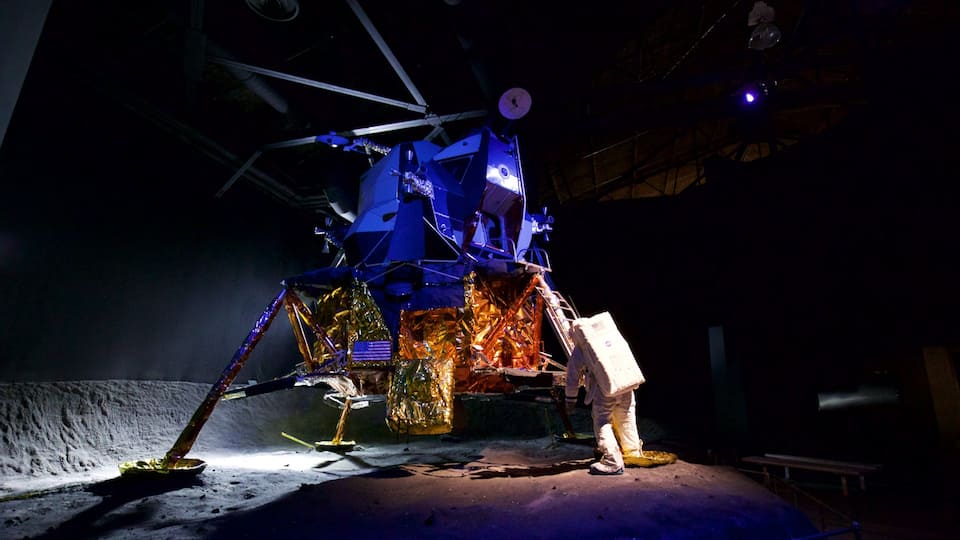 A space shuttle on display with a person standing beside it.