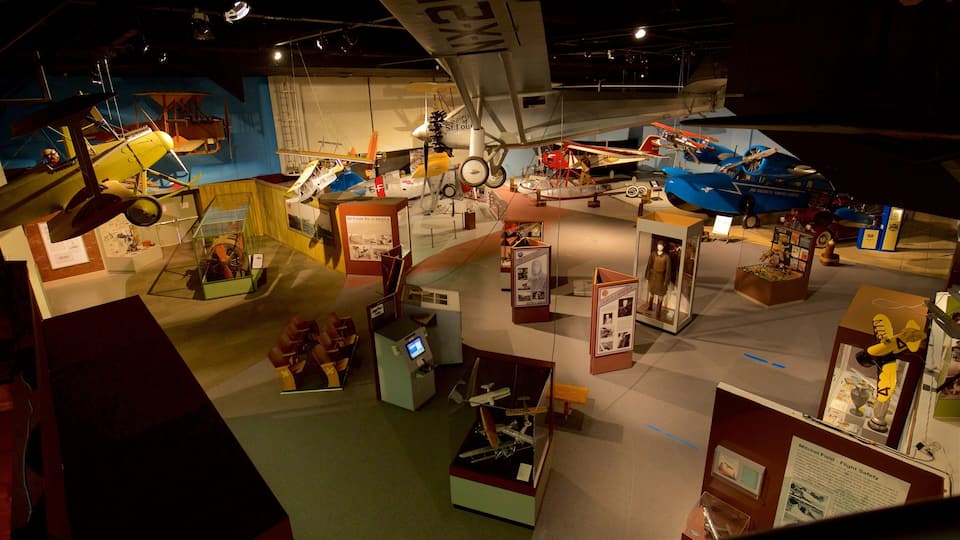 A museum exhibit with various aircraft models, including a yellow biplane and a blue monoplane.