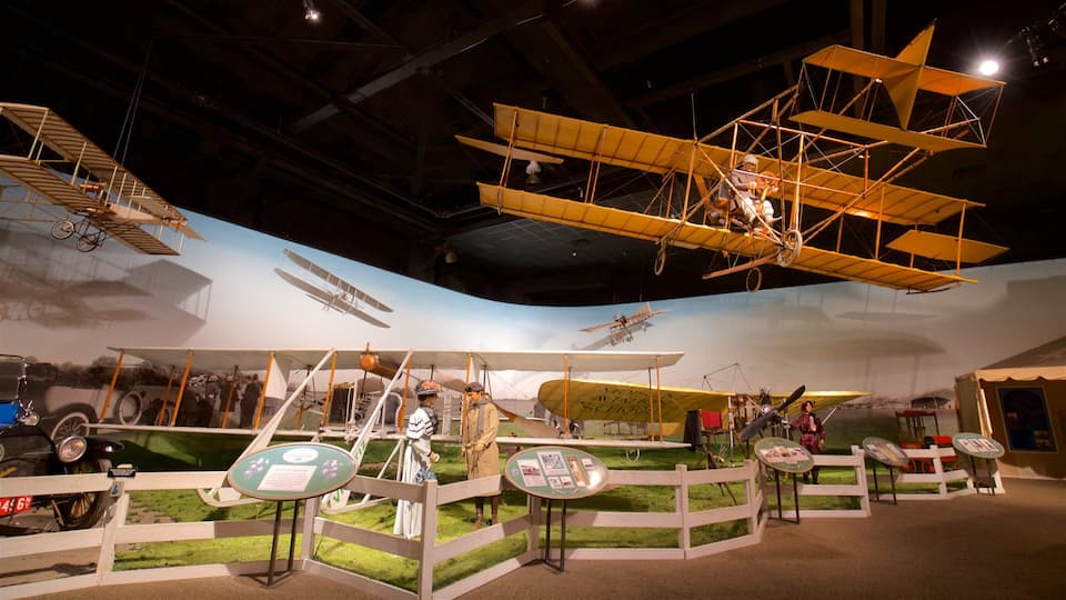 A museum exhibit with various historical biplanes and a vintage car.