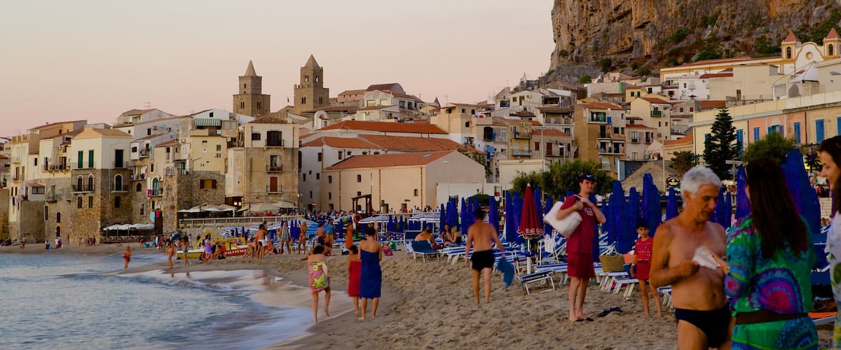 A coastal town with historic buildings, a beach, and a cliff.