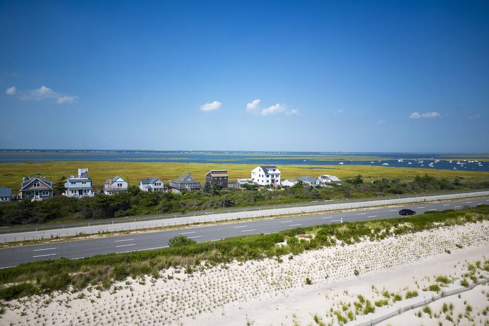 En kustväg med hus och en strand.