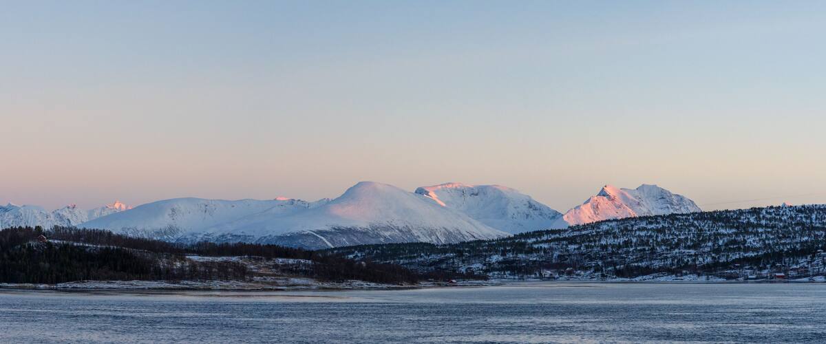 A snowy mountain range with a lake in the foreground.