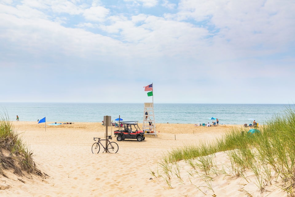 Una platja amb una bandera, una bicicleta i un vehicle de golf.