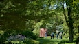 A garden with a statue, lush greenery, and a group of people walking.
