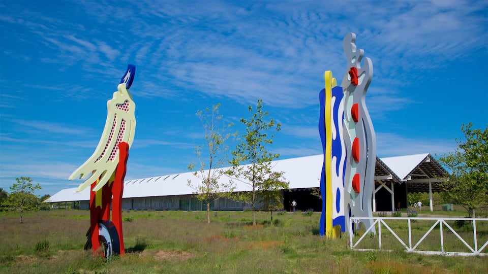 Two colorful sculptures in a grassy field with a white building in the background.