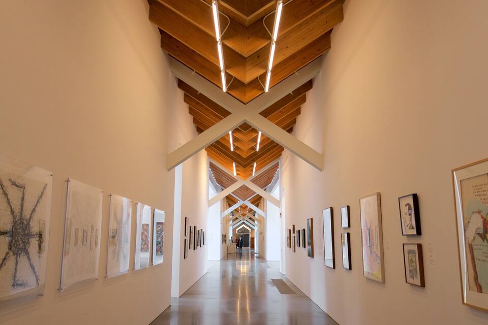Una galeria d'art amb un sostre de fusta i un llarg passadís que exhibeix diverses obres d'art.