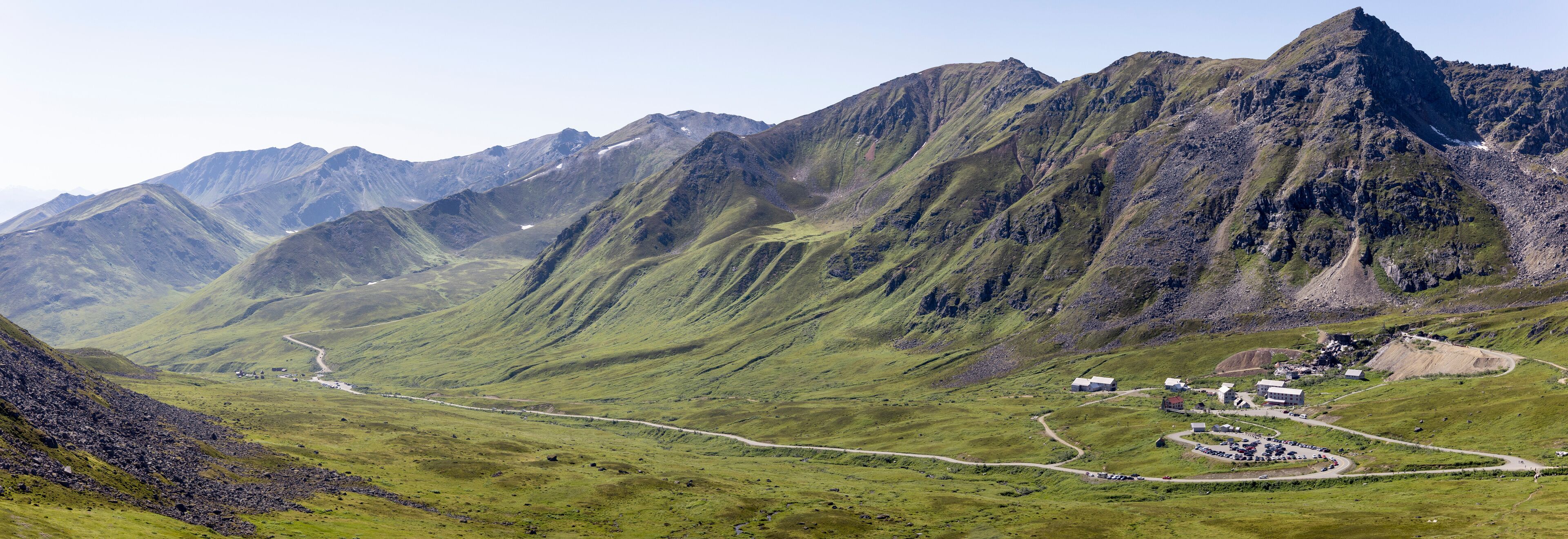 Independence Mine State Historical Park Visitor Center surrounded by the Talkeetna Mountains across Hatcher Pass under a sunny, blue sky; Palmer, Alaska, United States of America